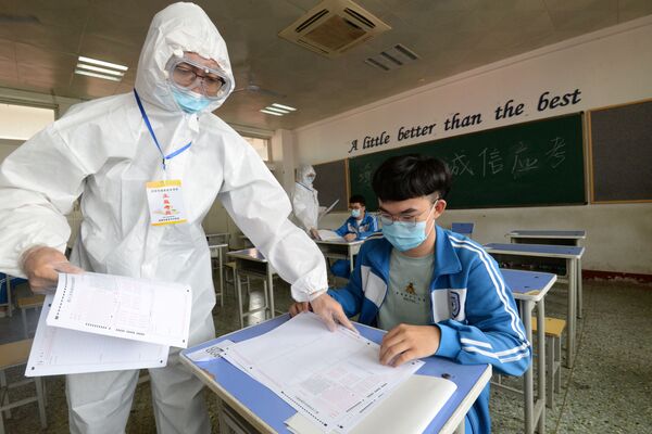 Экзаменатор раздает тестовые задания студентам на предварительном экзамене в Хандане, Китай - Sputnik Узбекистан