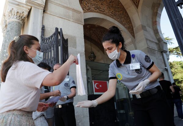 Студент в защитной маске показывает свои документы в главном кампусе Стамбульского университета в Стамбуле, Турция - Sputnik Узбекистан