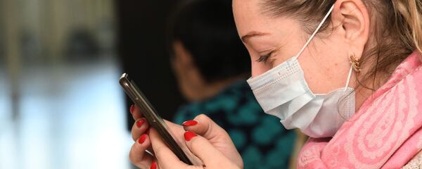 Девушка в защитной маске со смартфоном в руках - архивное фото Девушка в защитной маске со смартфоном в руках - архивное фото - Sputnik Ўзбекистон
