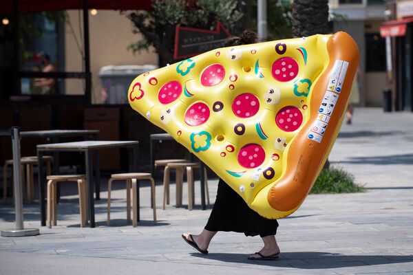 Женщина несет надувной матрас в форме пиццы в Барселоне. - Sputnik Узбекистан