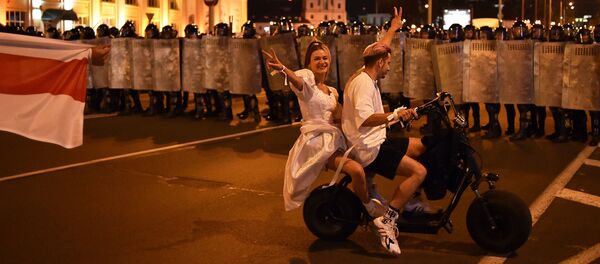 Para na skutere pered OMONom vo vremya aksii protesta posle zakritiya izbiratelnix uchastkov na prezidentskix viborax v Belarusi Para na skutere pered OMONom vo vremya aksii protesta posle zakritiya izbiratelnix uchastkov na prezidentskix viborax v Belarusi - Sputnik O‘zbekiston