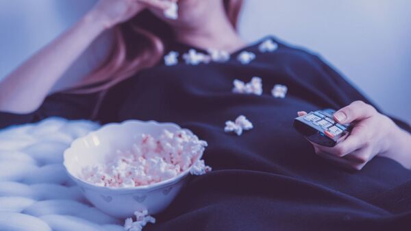 Девушка в постели ест попкорн и держит пульт. Архивное фото - Sputnik Ўзбекистон