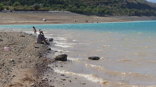 Уровень воды в водохранилище заметно упал, оголив глинистое дно. Многие предпочитают просто позагорать на берегу. - Sputnik Узбекистан