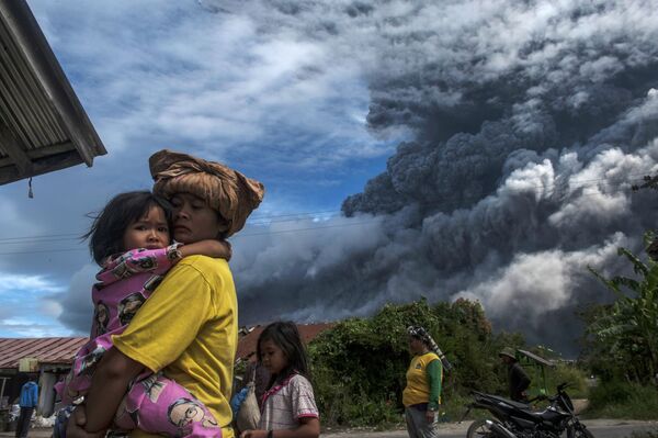 Местные жители в деревне у подножия действующего вулкана Синабунг в провинции Северная Суматра в Индонезии. - Sputnik Узбекистан