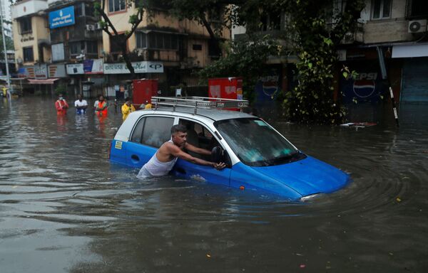 Мужчина толкает такси по затопленной улице после ливня в Мумбаи, Индия. - Sputnik Узбекистан