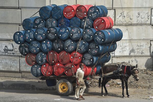Мужчина рядом с повозкой, груженной бочками с нефтью, на улице в Лахоре, Пакистан. - Sputnik Узбекистан