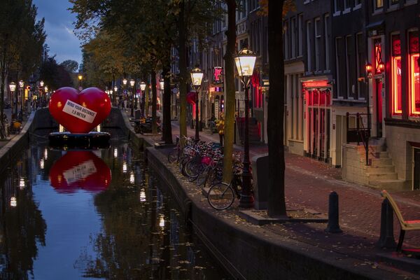 Красное сердце с напоминанием соблюдать социальную дистанцию в почти пустом квартале красных фонарей в Амстердаме, Нидерланды - Sputnik Ўзбекистон