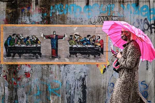 Женщина в леопардовой защитной маске на фоне граффити итальянского художника TvBoy в Милане, Италия - Sputnik Узбекистан