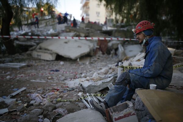 Спасатель во время отдыха на месте разрушенного здания после землетрясения в Измире  - Sputnik Узбекистан