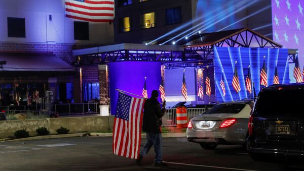 Сторонник Байдена с флагом в день выборов президента в штате Делавер, США - Sputnik Ўзбекистон