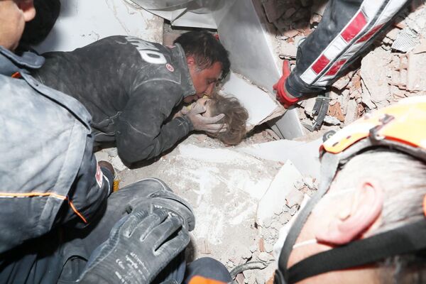 Спасатели вытаскивают ребенка из-под завала в результате землетрясения в Измире, Турция - Sputnik Узбекистан