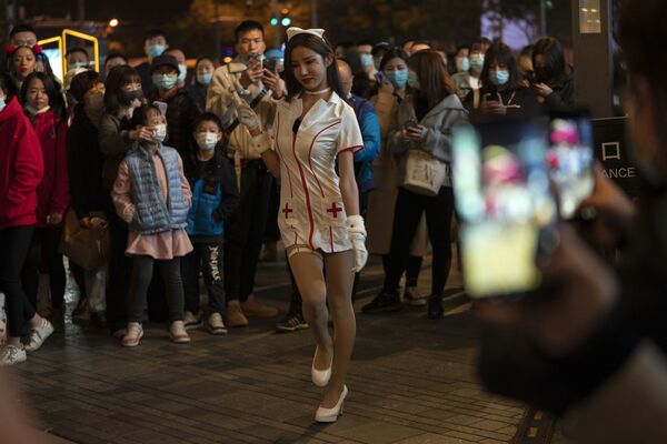 Девушка в костюме медсестры выступает перед толпой в ночь Хэллоуина в торговом районе Пекина - Sputnik Узбекистан