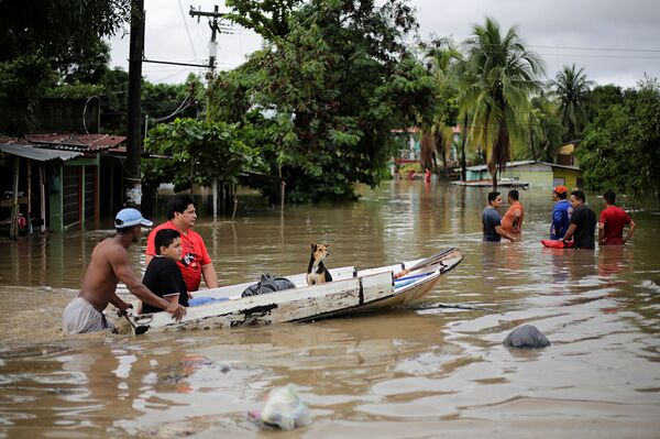 Люди толкают лодку с собакой по затопленной после шторма улице в Ла-Лима, Гондурас - Sputnik Узбекистан