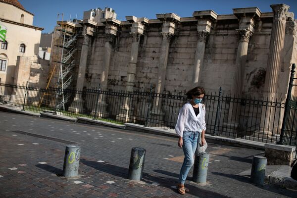 Девушка в защитной маске проходит мимо места археологических раскопок в Библиотеке Адриана во время локдауна, объявленного правительством в связи с коронавирусом, в Афинах, Греция - Sputnik Узбекистан