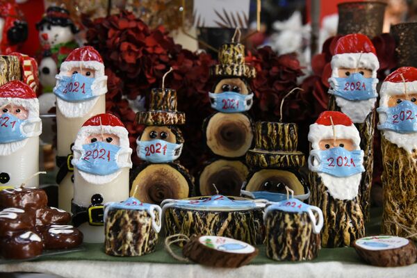 Рождественские свечи в виде Санта-Клаусов в масках в магазине в Греции  - Sputnik Узбекистан