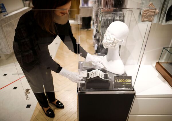 Сотрудник магазина устанавливает маску с драгоценными камнями  в Токио  - Sputnik Узбекистан