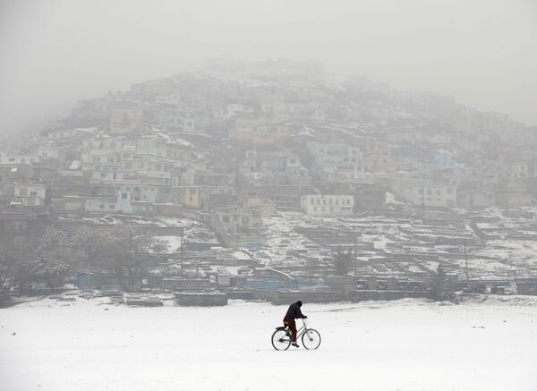 Велосипедист во время снегопада на фоне заснеженного Кабула, Афганистан - Sputnik Ўзбекистон