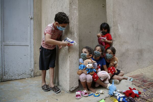 Пакистанские дети в защитных масках играют возле своего дома в Газе - Sputnik Узбекистан