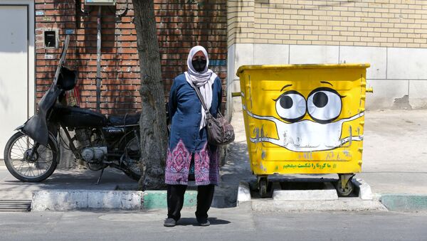 Женщина в защитной маске у разрисованного мусорного бака в Тегеране  - Sputnik Ўзбекистон
