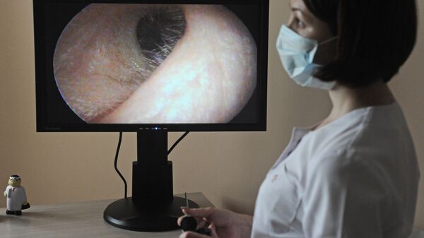 Врач-отоларинголог просматривает запись осмотра уха пациента - Sputnik Узбекистан