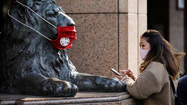 Женщина в защитной маске перед статуей в Токио  - Sputnik Ўзбекистон