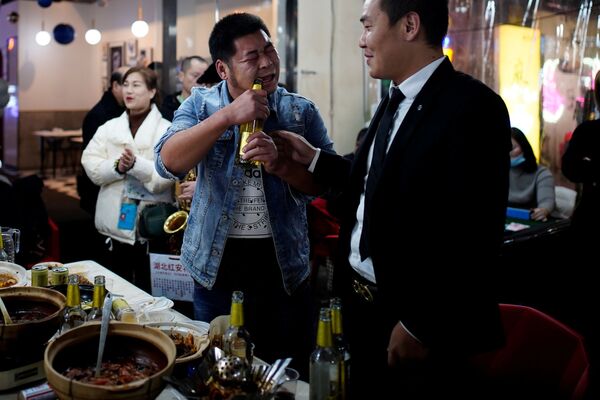 Мужчина открывает пиво зубами в одном из ресторанов Уханя - Sputnik Узбекистан