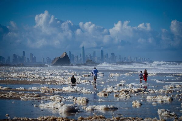 Туристы гуляют среди пены на пляже после циклона на пляже в Австралии. - Sputnik Узбекистан