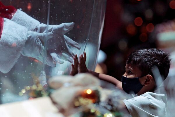 Ребенок общается с Санта Клаусом через пластиковый экран в шоппинг-центре в Бразилии. - Sputnik Узбекистан