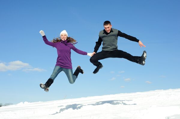 Подпрыгнувшая пара на фоне снега и голубого неба - Sputnik Ўзбекистон