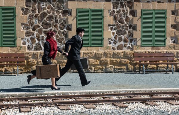 Парень и девушка с винтажными чемоданами в руках бегут по перрону - Sputnik Ўзбекистон
