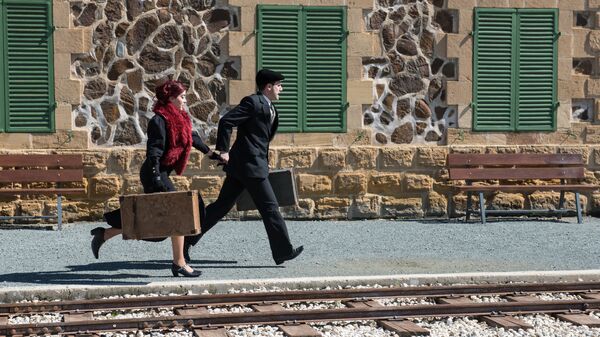 Парень и девушка с винтажными чемоданами в руках бегут по перрону - Sputnik Узбекистан