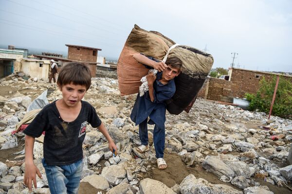Молодые люди спасают остатки вещей из развалин домов после внезапного наводнения в Чарикаре, провинция Парван, Афганистан - Sputnik Узбекистан