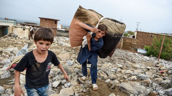 Молодые люди спасают остатки вещей из развалин домов после внезапного наводнения в Чарикаре, провинция Парван, Афганистан - Sputnik Узбекистан