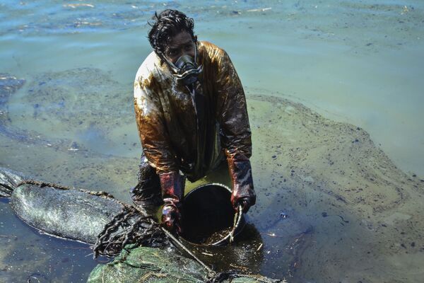 Мужчина очищает воду от разлившейся у берегов Маврикия нефти - Sputnik Узбекистан