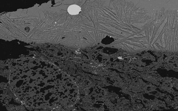 Изображение шлака внутри тигля, полученное с помощью сканирующего электронного микроскопа, с серебристым стальным пятном, видимым в центре вверху - Sputnik Узбекистан