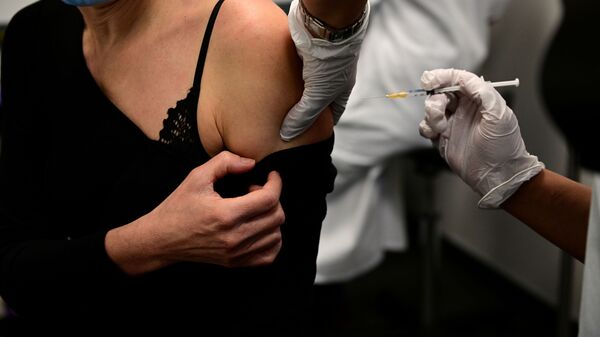 Женщина получает вакцину от COVID-19 во время кампании вакцинации медицинских работников в центре вакцинации в Париже - Sputnik Ўзбекистон