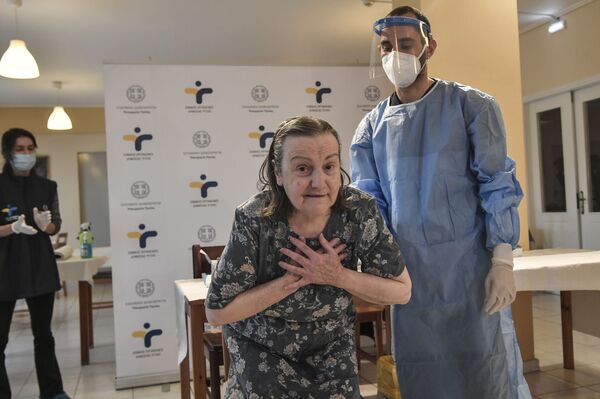 Женщина выражает благодарность после вакцинации в доме престарелых в пригороде Афин, Греция. - Sputnik Узбекистан