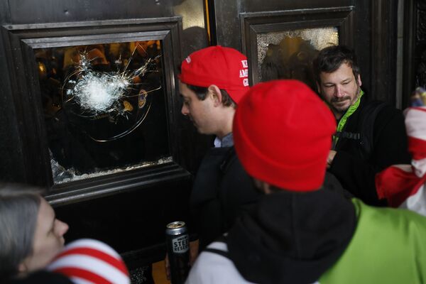 Участники протеста у разбитой двери Капитолия. - Sputnik Узбекистан