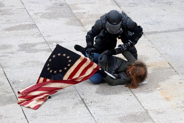 В Вашингтоне полицейский пытается задержать протестующую у здания конгресса. - Sputnik Узбекистан