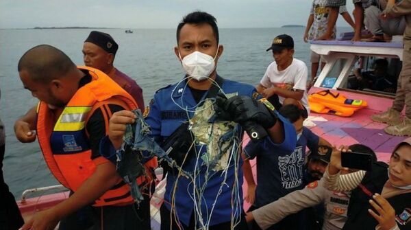 Член поисково-спасательной группы демонстрирует найденный в море обломок самолета Boeing 737 - Sputnik Узбекистан