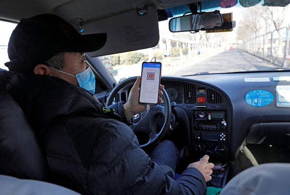 Водитель такси показывает QR-код регистрации здоровья пассажиру для сканирования перед поездкой в Пекине. - Sputnik Узбекистан