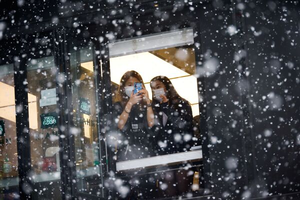 Девушки фотографируют снегопад в Сеуле. - Sputnik Узбекистан