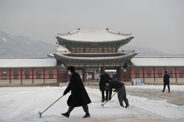 Люди в масках очищают территорию дворцового комплекса Кенбоккун в Сеуле. - Sputnik Узбекистан
