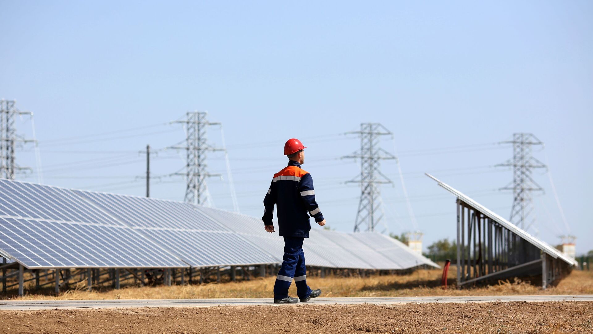 Сотрудник осматривает состояние фотоэлектрических элементов на солнечных панелях солнечной электростанции - Sputnik Узбекистан, 1920, 06.04.2021