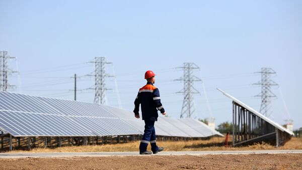 Сотрудник осматривает состояние фотоэлектрических элементов на солнечных панелях солнечной электростанции - Sputnik Узбекистан