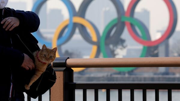 Мужчина с котом в сумке на фоне олимпийских колец в Токио - Sputnik Узбекистан