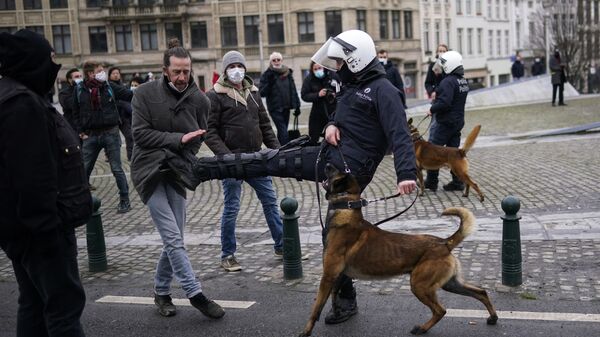 Полицейский бьет ногой демонстранта во время несанкционированной демонстрации против ограничительных мер COVID-19 в Брюсселе  - Sputnik Узбекистан