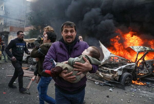 Мужчина несет на руках ребенка, пострадавшего в результате взрыва заминированного автомобиля в сирийском городе Азаз. - Sputnik Узбекистан
