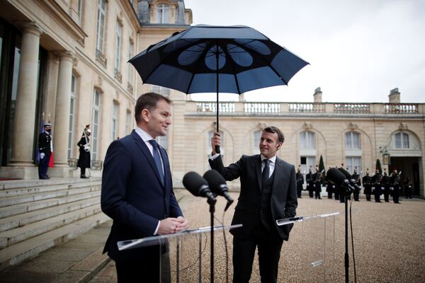 Президент Франции Эммануэль Макрон держит зонтик над премьер-министром Словакии Игорем Матовичем во время совместного заявления в Елисейском дворце в Париже. - Sputnik Узбекистан