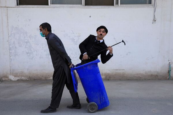 Мужчина в костюме Чарли Чаплина в мусорном баке во время представления в Пешаваре, Пакистан. - Sputnik Узбекистан